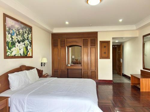 a bedroom with a large bed with a painting on the wall at Khách Sạn Mường Thanh Grand Gia Lai in Pleiku