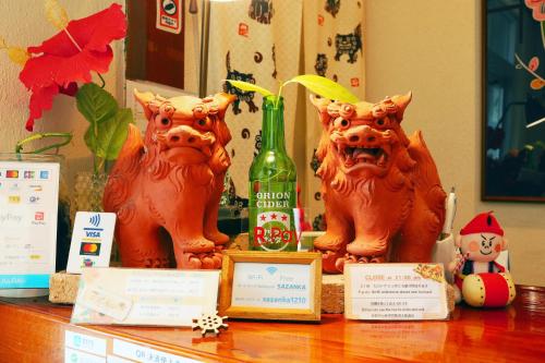 a table with three foo dogs and a bottle of wine at 民宿さざんか in Okinawa City