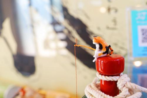 a toy bird sitting on top of a red fire hydrant at 民宿さざんか in Okinawa City