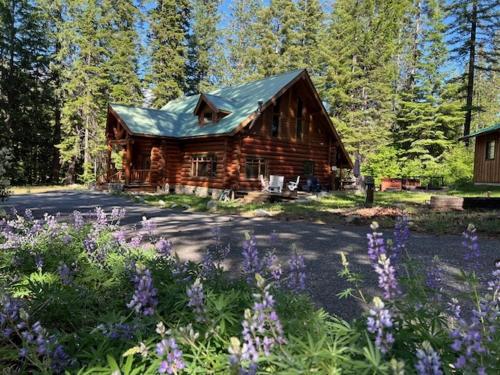 a log cabin with purple flowers in front of it at Soaring Pines Lodge by NW Comfy Cabins in Leavenworth