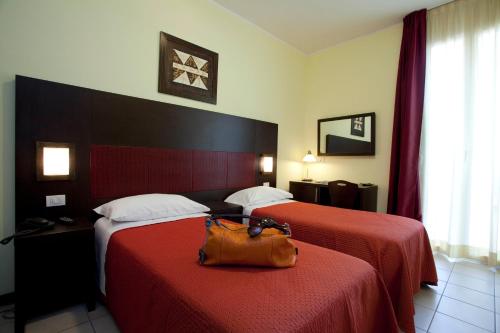 una camera d'albergo con due letti con una borsa sopra di Hotel Alibi a Rimini