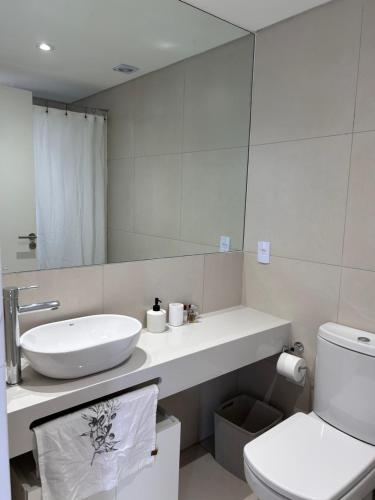 Un baño con lavabo, inodoro y espejo. en Excelente Apartamento en calle Moldes, en Buenos Aires