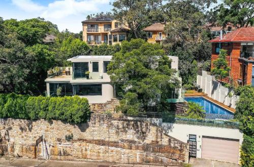 a house on a hill with a brick wall at 6BR Stunning Waterview & Private Pool in Sydney