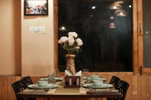 a table with a vase of pink flowers on it at The Bagh Kufri in Kūfrī