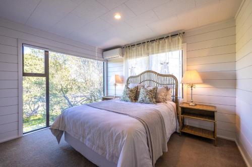 ein Schlafzimmer mit einem Bett und einem großen Fenster in der Unterkunft Viletta Hauraki by Waiheke Pure in Waiheke Island