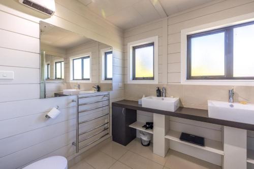 ein Badezimmer mit zwei Waschbecken und zwei Spiegeln in der Unterkunft Viletta Hauraki by Waiheke Pure in Waiheke Island