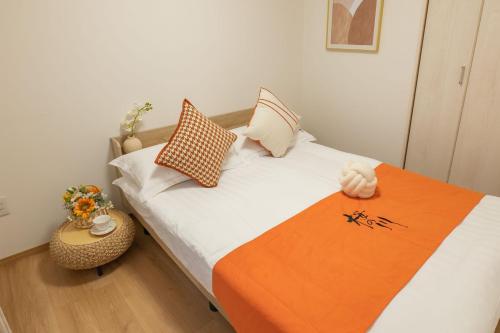 a bed with an orange blanket and pillows on it at 桜の川38 新宿渋谷に直結 幡ヶ谷一戸建 2-11人丨 connected to Shinjuku and Shibuya House 2-11 people in Tokyo