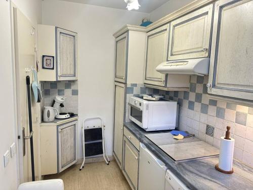 Il comprend une petite cuisine équipée d'un four micro-ondes et d'un comptoir. dans l'établissement Appartement spacieux avec terrasse vue port, parking inclus - FR-1-252A-133, à Villeneuve-Loubet