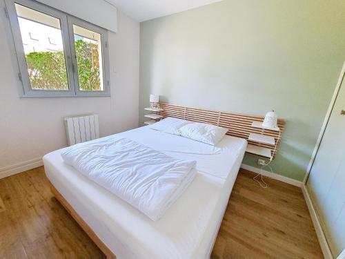 une chambre avec un lit blanc et une fenêtre dans l'établissement Appartement Rez-de-Jardin Proche Mer, 4 Couchages - FR-1-746-31, à Bernières-sur-Mer