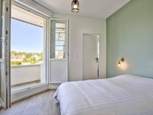une chambre avec un lit et une grande fenêtre dans l'établissement Appartement lumineux avec 2 balcons à 600m de la plage - FR-1-788-78, à Merville-Franceville-Plage