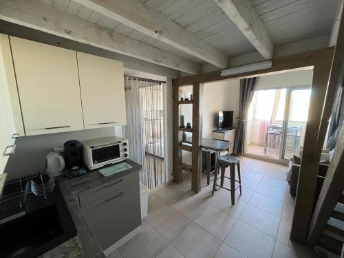 une cuisine avec un comptoir et une table avec un micro-ondes dans l'établissement Appartement 2 pièces près de la plage avec mezzanine et parking - FR-1-338-621, à Sète