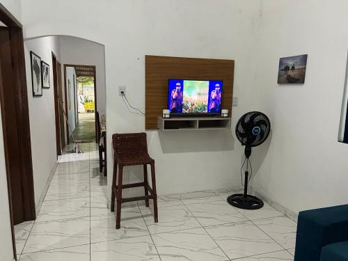 a living room with a flat screen tv on a wall at Casa aconchegante em Barra de Caravelas in Caravellas