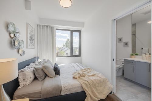 ein weißes Schlafzimmer mit einem Bett und einem Badezimmer in der Unterkunft Fenced Yard, Free Parking, 2 King Beds with AC in Calgary