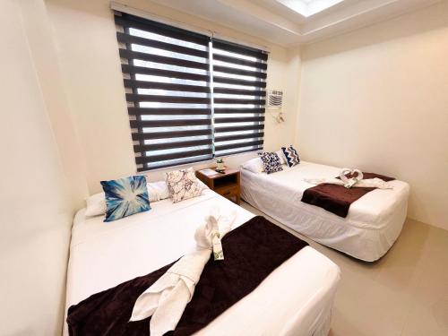 two beds in a room with a window at Taylors Plantacion Resort- Grande Second Floor in Catarman