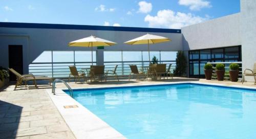 ジョアンペソアにあるHotel Tambau Flat particular908のスイミングプール(テーブル、椅子、パラソル付)