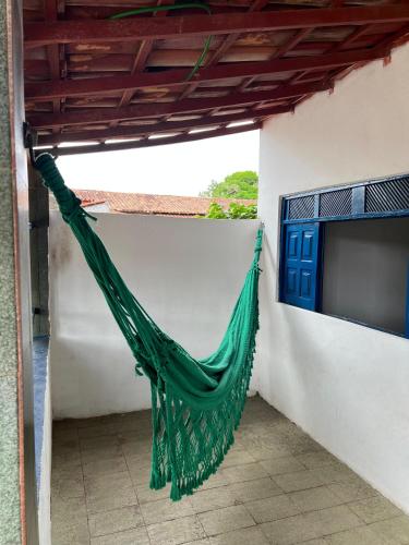 a green hammock hanging on the side of a building at Casa aconchegante em Barra de Caravelas in Caravellas