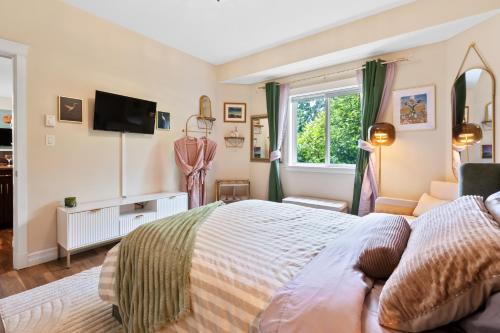 a bedroom with a bed and a tv on the wall at The Velvet Fern Guesthouse in Courtenay