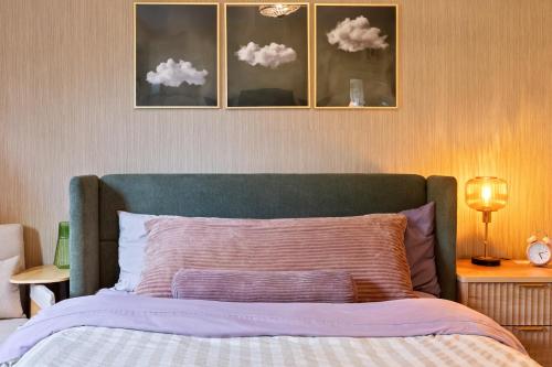 a bed with a green headboard with clouds on the wall at The Velvet Fern Guesthouse in Courtenay
