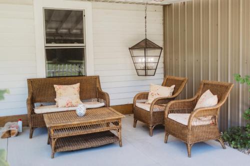 three wicker chairs and a table on a porch at Serene Studio Country Apartment in Sawyer MI Near Lake MI and Downtown in Harbert
