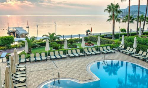 a resort with a pool and chairs and a beach at Golden Lotus Hotel in Kemer
