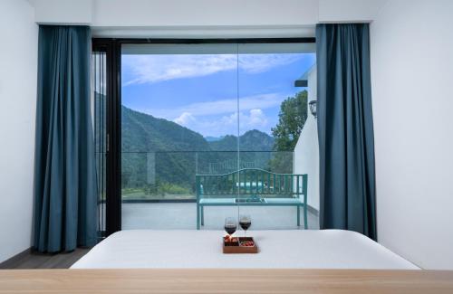 a bedroom with a bed and two glasses of wine at Healing House--Free one way pick up service over 2 nights in Zhangjiajie