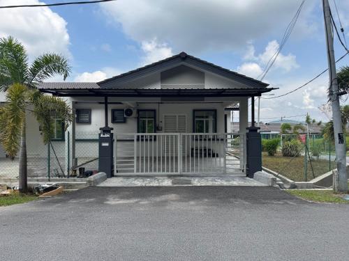 a small white house with a gate at Homestay D BBSE in Simpang Empat