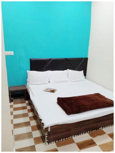 a bed with white sheets and a blue wall at HOTEL Priyanshi !Palace Near Shri Mahakaleshwar Jyotirlinga Temple - Fully Air Conditioned Rooms With Wi-fi - Free Parking Available in Ujjain