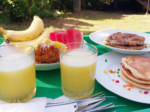 a table with plates of food and two glasses of orange juice at Lake Cabin in Polonnaruwa