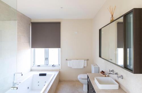 a bathroom with a tub and a sink and a toilet at Eco-Luxe @ Mount Avoca in Avoca