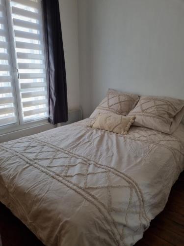 un lit avec des draps et des oreillers blancs et une fenêtre dans l'établissement Comfy studio, à Paris