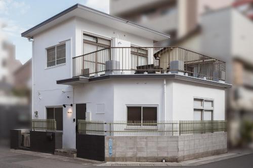 a white house with a balcony on a street at YokaYado Kagoshima Chuo - Retro Style Japanese Modern Entire House with Rooftop Balcony in Kagoshima