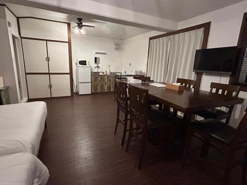 a living room with a dining room table and a kitchen at Pine house in Churaumi in Motobu