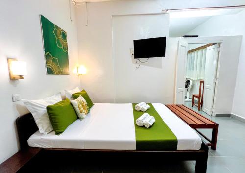 a bedroom with a bed with green pillows and a tv at STEPHEN HOTEL in Toamasina