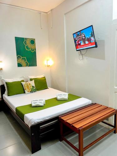 a bed in a room with a tv on the wall at STEPHEN HOTEL in Toamasina