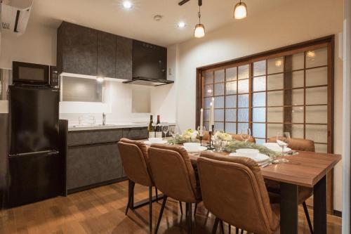 a kitchen with a table with chairs and a refrigerator at YokaYado Kagoshima Chuo - Retro Style Japanese Modern Entire House with Rooftop Balcony in Kagoshima