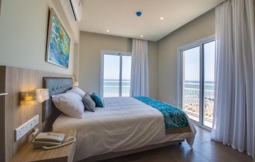 a bedroom with a bed with a view of the ocean at Zodiac Hotel Apartments in Larnaka
