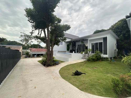 Un gato negro tendido en el césped frente a una casa. en Chao Pao Villa Phase 2, en Ko Pha Ngan