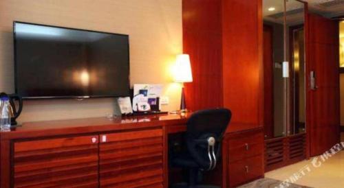 a room with a desk with a television and a chair at Xiamen Jingmin Central Hotel in Xiamen
