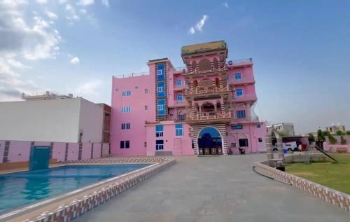 ein rosafarbenes Gebäude mit einem Pool davor in der Unterkunft Hill view resort in Jaipur