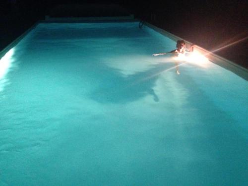 a person swimming in a swimming pool at night at Appartamento con piscina e tennis in Montespertoli