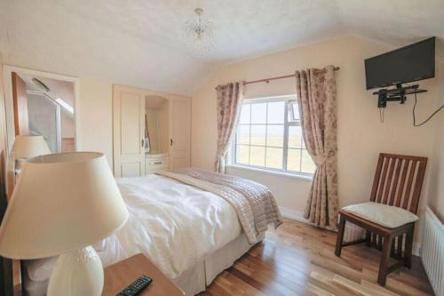 1 dormitorio con 1 cama, TV y silla en Bru Chlann Lir, en Belmullet