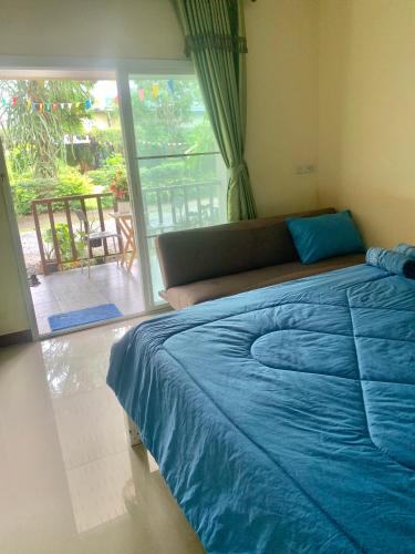 a bedroom with a blue bed and a sliding glass door at นิลแลนด์ รีสอร์ท in Ban Tha Dan