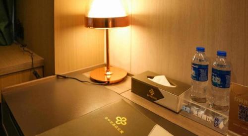 a desk with a lamp and two bottles of water at Golden Central Hotel Shenzhen in Shenzhen