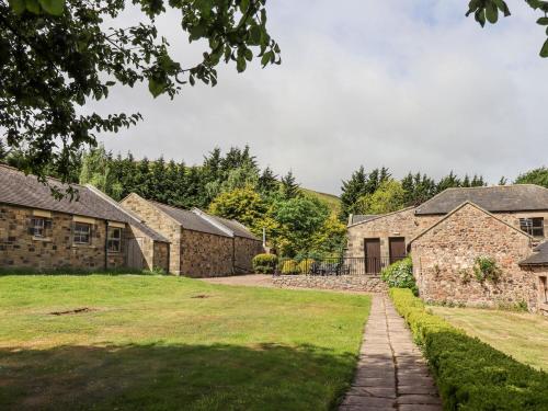 a row of stone houses with a grass yard at Heatherview in Wooler