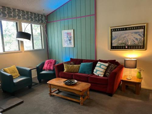 a living room with a red couch and two chairs at Eagle Summit Collection in Mammoth Lakes
