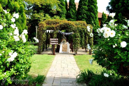 a garden with an arch with a table and white flowers at Midrand Conference Centre in Midrand