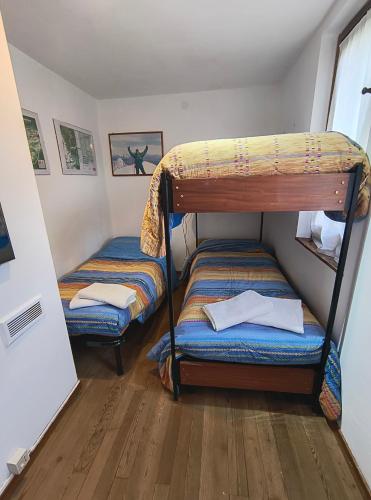 two bunk beds in a room with wooden floors at Refuge d'Entreves - Chalet con Balcone, Giardinetto e Vista Monte Bianco - Horizon Vacanze in Courmayeur