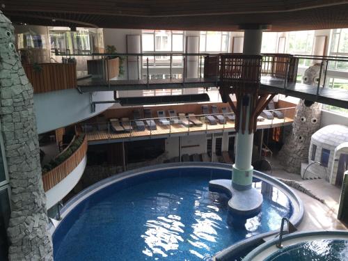 a large swimming pool in a building with chairs at MenDan Magic Spa & Wellness Hotel in Zalakaros