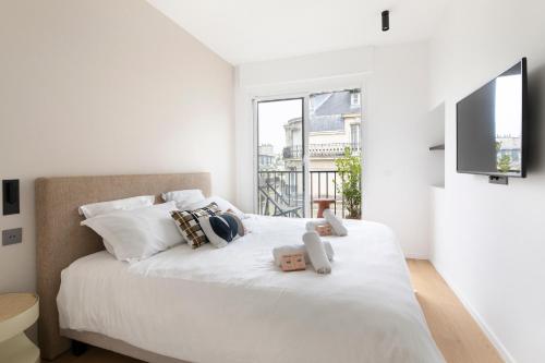 - une chambre blanche avec un grand lit et une télévision murale dans l'établissement Bright & Chic apartment Near Porte Maillot - 4P, à Neuilly-sur-Seine