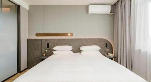a bedroom with a large white bed with two pillows at Jinjiang Inn Qingdao Development Zone Jinggangshan Rd. in Huangdao